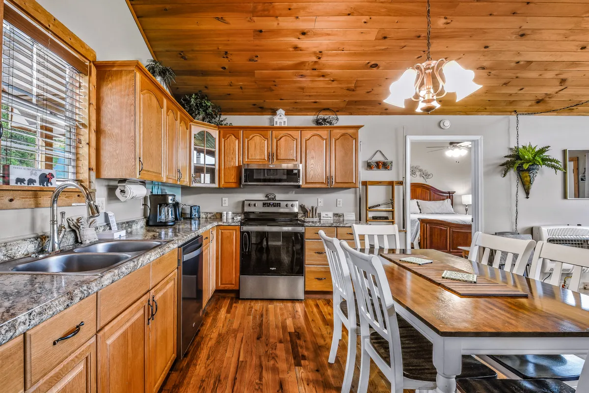 A cozy kitchen and dining space with wooden cabinets, a central island for meal prep, and a large dining table adorned with comfortable seating—inviting for both casual breakfasts and festive dinners.
